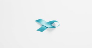 Vertical video of pale blue prostate cancer awareness ribbon on white background with copy space. Cancer, health awareness, medical support and healthcare concept.