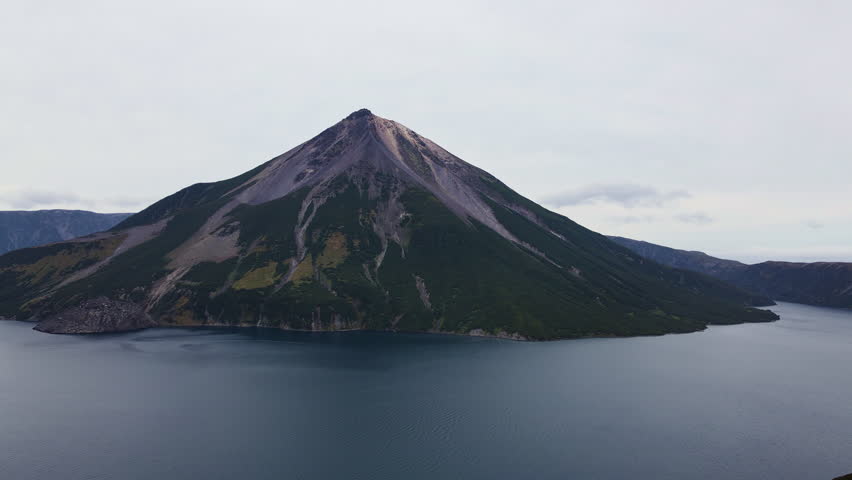 Aerial view of the unique Krenitsyn volcano on Onecotan Island. The volcanic cone rises as an island inside Lake Koltsevoye. The lake is surrounded by somma. Walls of the older caldera Tao-Rusyr | Shutterstock HD Video #1099467165