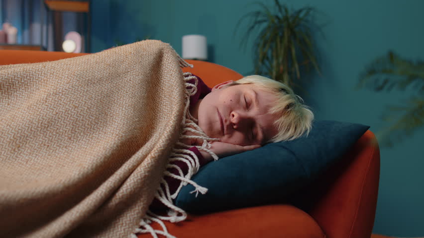 Tired young woman with short blonde hair lying down in bed taking a rest at home room. Carefree girl napping, falling asleep on comfortable sofa with pillows. Closed her eyes enjoy night nap alone | Shutterstock HD Video #1099469845