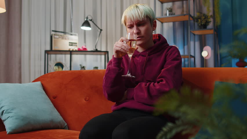 Sad woman girl with short hair sitting at home looks pensive of unrequited love, suffers from unfair situation, drinking champagne. Problem, break up, depressed feeling bad annoyed, burnout bankruptcy | Shutterstock HD Video #1099469847