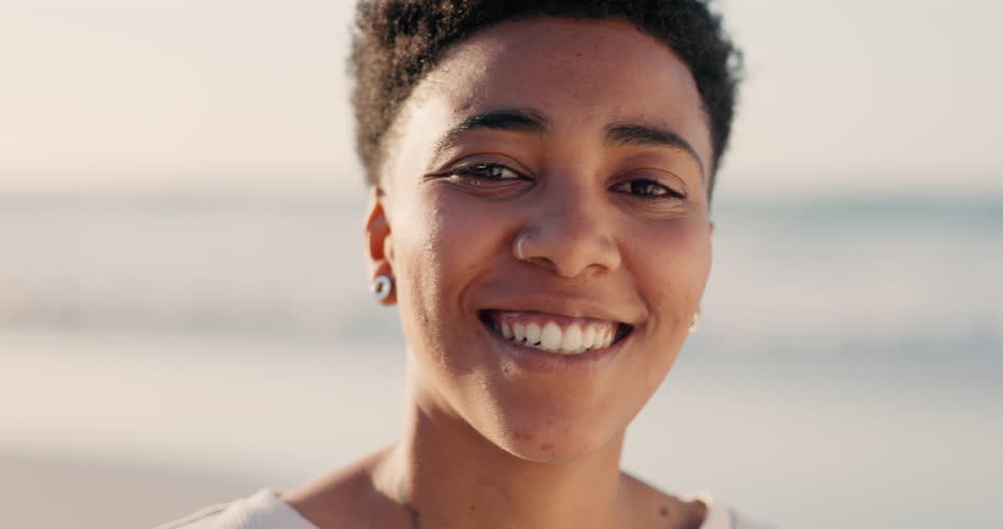 Happy black woman at beach, natural portrait on outdoor vacation and bright smile of teeth. Sunset at sea with young person girl and androgynous freedom in travel lifestyle with positive mindset | Shutterstock HD Video #1099473199