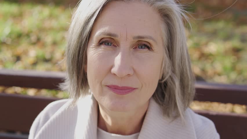 Mature woman with stylish gray hair looking at camera with serious face expression spending time outdoor, feeling social protection, guarantees from the state for pensioners | Shutterstock HD Video #1099474815