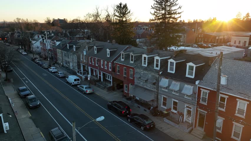 Slow aerial pass by row houses in American city. Beautiful sunset over winter scene.