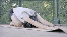 Close-up of a young hippie latin man with long hair doing yoga on a mat and changing position on camera. 4k video