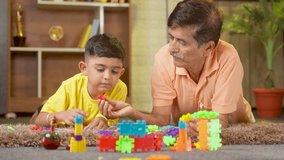 relaxed grandfather playing with grandson using toys on floor at home - concept of knowledge, retirement lifestyle and family bonding. - Powered by Shutterstock - Get 15% off with code: PIKWIZARD15