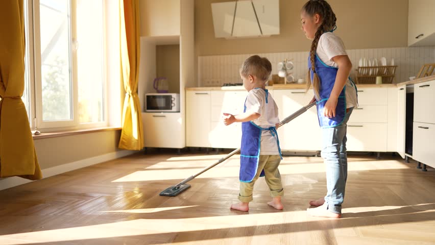 Happy children at home mopping floors.Clean house cleaning.Cute child work at home.Clean interior.Domesticated child washes floors with mop.Completion of assigned task.Teaching children about homework | Shutterstock HD Video #1099487985
