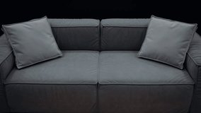 A simple gray sofa with cushions of the same color, shot slowly on a black background. 4k video