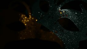 Two luxury traditional venetian masks on dark background illuminated and sparkles from the darkness. Blue and gold shiny carnival masquerade fantasy mask with small colorful stars under light in dark - Powered by Shutterstock - Get 15% off with code: PIKWIZARD15