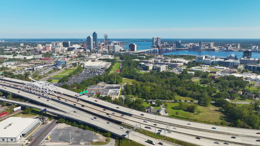 Aerial view of Jacksonville city with high office buildings and american freeway intersection with fast driving cars and trucks. View from above of USA transportation infrastructure