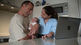 Mom and dad admiring baby and using laptop