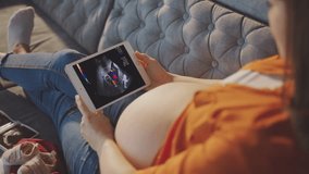 Back view of pregnant woman watching ultrasound report video on her tablet