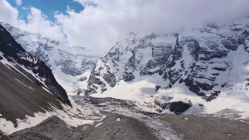 Breathtaking scenery of the Mizhirgi Glacier and the Northern Wall in the Bezengi Gorge. Snow-capped mountains. Wild untouched nature of the Caucasus Mountains. Bezengi Gorge. White clouds Aerial view