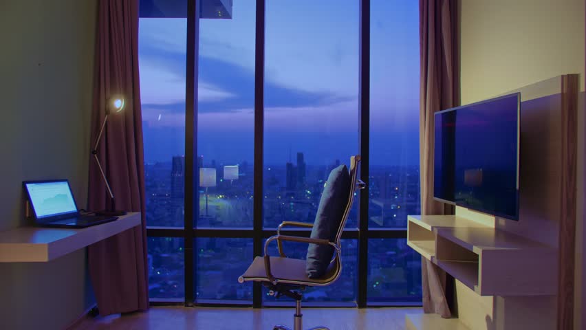 Handsome man in room luxury hotel works at laptop. Nice guy lives or freelancing works in hotel. Man in an apartment against background of night city. Man sits on an office chair against large window | Shutterstock HD Video #1099500811