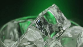 Super slow motion poured alcohol liquid on spin ice cubes in turn glass.Slow motion 1000 fps on pouring brown liquid on ice cubes in rotate glass.Slow motion pours steam ice cubes on green background - Powered by Shutterstock - Get 15% off with code: PIKWIZARD15