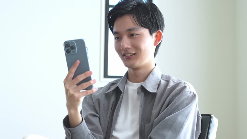 Asian man looking at his phone with a smile | Shutterstock HD Video #1099503211