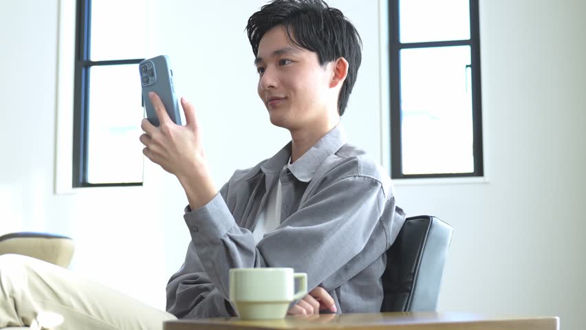 Asian man looking at his phone with a smile | Shutterstock HD Video #1099503481