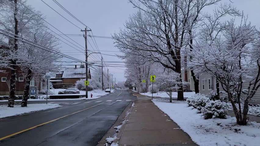 A suburban street on snowy winter day under a cloudy sky.