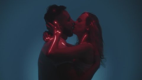 A young couple is kissing in the studio. A man and a woman make a kiss with their lips, a laser shines. A guy and a girl are hugging, in love. Honeymoon after the wedding, prelude before sex Stock-video