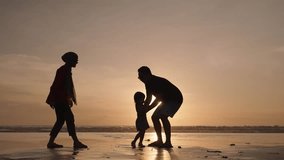 Happy Modern Muslim Southeast Asian Indonesian Family Enjoying Sunset Together on The Beach. Silhouette of Father Mother and Child in Slow Motion. - Powered by Shutterstock - Get 15% off with code: PIKWIZARD15