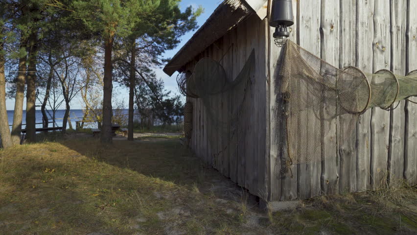 Fishing houses with tackle in the dunes of the Baltic. Lamp and nets on vintage wooden houses in the village of Ragaciems. Sunny autumn day in Kurzeme in the Gulf of Riga. Latvia, Baltic.