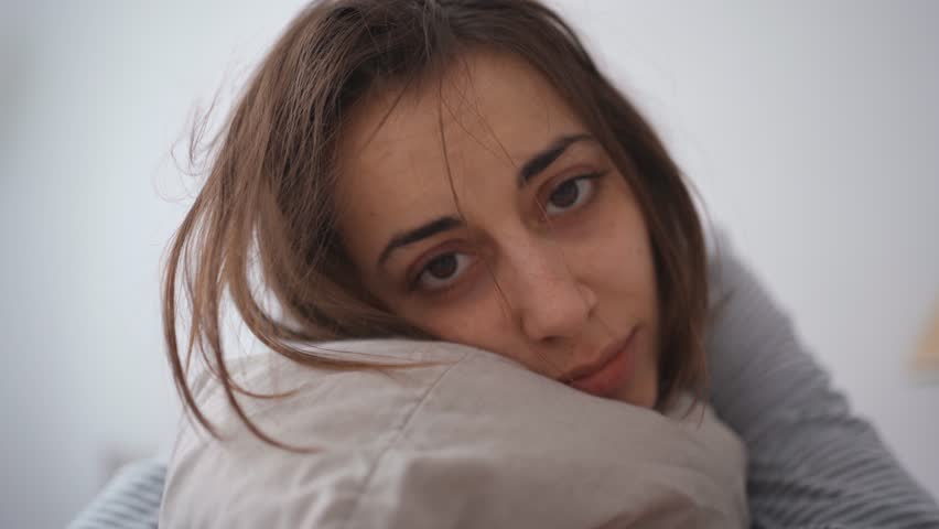 Young woman lies alone on bed at home, cold and sick. illness, cold, virus, doctor's call at home, consultation with a doctor by phone | Shutterstock HD Video #1099514013