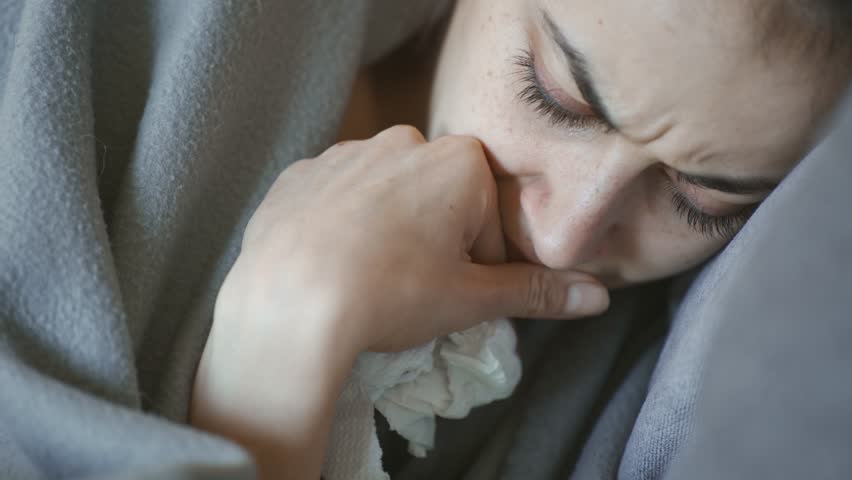 Young woman lies alone on bed at home, cold and sick. illness, cold, virus, doctor's call at home, consultation with a doctor by phone | Shutterstock HD Video #1099514015