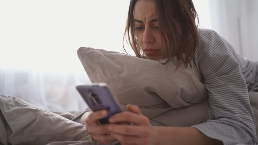 young woman lies alone on bed at home, cold and sick. illness, cold, virus, doctor's call at home, consultation with a doctor by phone