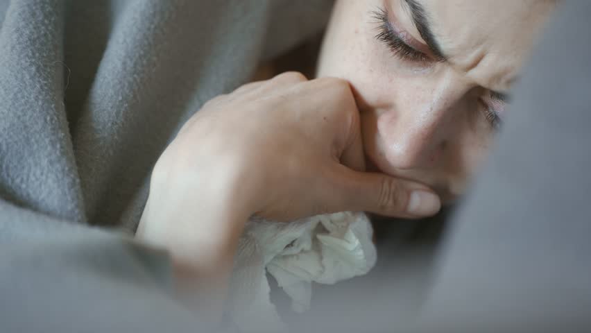 young woman lies alone on bed at home, cold and sick. illness, cold, virus, doctor's call at home, consultation with a doctor by phone