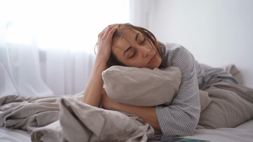 young woman lies alone on bed at home, cold and sick. illness, cold, virus, doctor's call at home, consultation with a doctor by phone