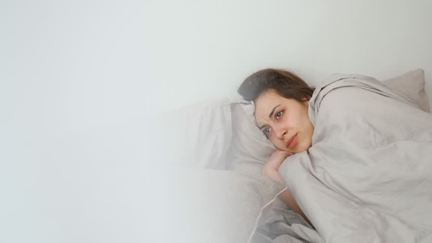 young woman lies alone on bed at home, cold and sick. illness, cold, virus, doctor's call at home, consultation with a doctor by phone