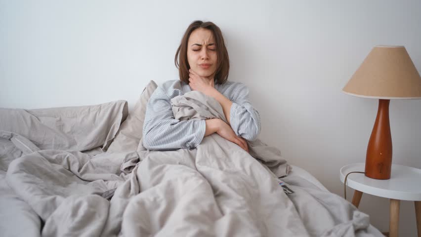 young woman lies alone on bed at home, cold and sick. illness, cold, virus, doctor's call at home, consultation with a doctor by phone