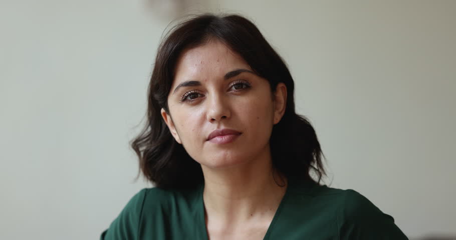 Pretty black haired young Asian woman posing indoors, looking at camera with positive, happy, cheerful face expression smiling, laughing, showing healthy teeth. Beautiful lady head shot video portrait