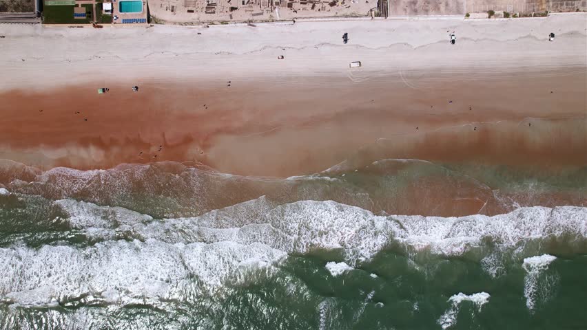 Aerial view of waves hitting the Daytona beach, in Florida, USA - top down, drone shot