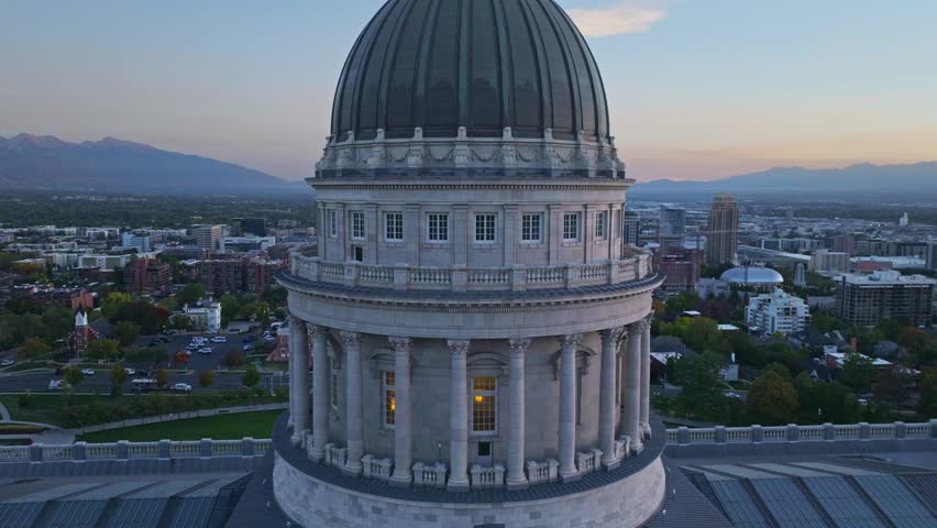 Utah State Capitol with beautiful view of the modern Salt Lake City skyline after sunset. Drone panning away shot