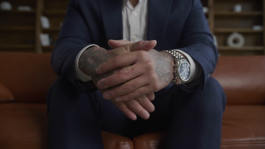 Extreme close up of businessman hands covered in tattoo wearing a suit squashed in slow motion
