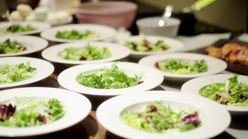 Serve salad on plates for several people. The salad is laid out on white plates for dinner. Dinner concept for a group of people. | Shutterstock HD Video #1099518315
