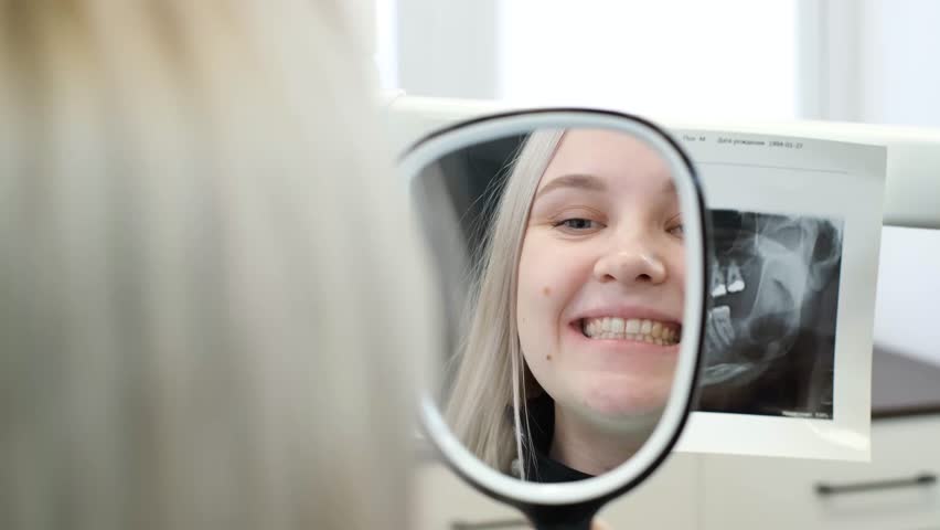 A satisfied patient looks at the healed teeth in the dental mirror.  | Shutterstock HD Video #1099518865