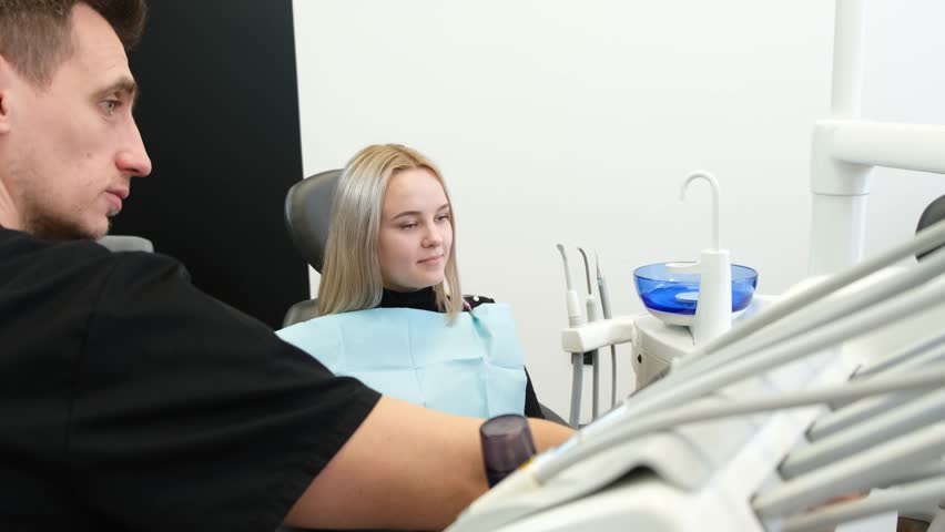 Consultation of a dentist and a female patient. In the dental chair. | Shutterstock HD Video #1099518867