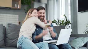 Young married couple with credit card shopping online paying bills or order food delivery using laptop sitting on the couch at home Happy family buying on internet and making payment on computer - Powered by Shutterstock - Get 15% off with code: PIKWIZARD15
