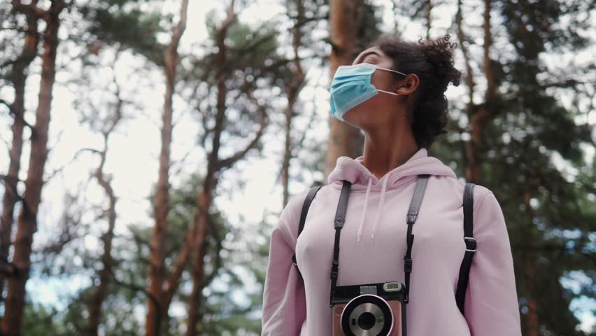 Lifestyle during covid-19, quarantine. Young black woman putting off medical protective mask making selfie during walking in summer park, tourist after covid | Shutterstock HD Video #1099522003