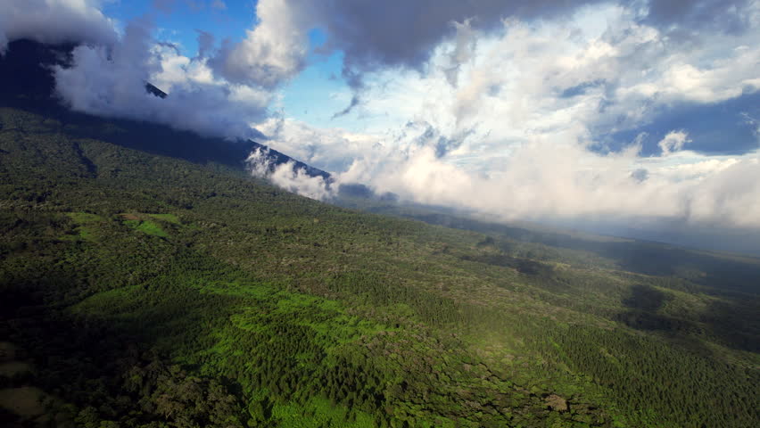 Fly over a forested volcano in Guatemala via drone. See blue skies, clouds, and nature in a peaceful, scenic, and relaxing video. A serene and tranquil visual experience | Shutterstock HD Video #1099524339