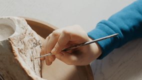 The process of painting a stone in an art studio. Media. Close-up of an artist's hand with a brush - Powered by Shutterstock - Get 15% off with code: PIKWIZARD15
