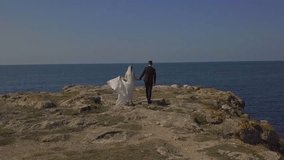 The bride and groom in wedding clothes are walking along the seashore, hugging, kissing, running, enjoying themselves. Husband and wife are filming a clip in a hotel on vacation. Lovely couple look at