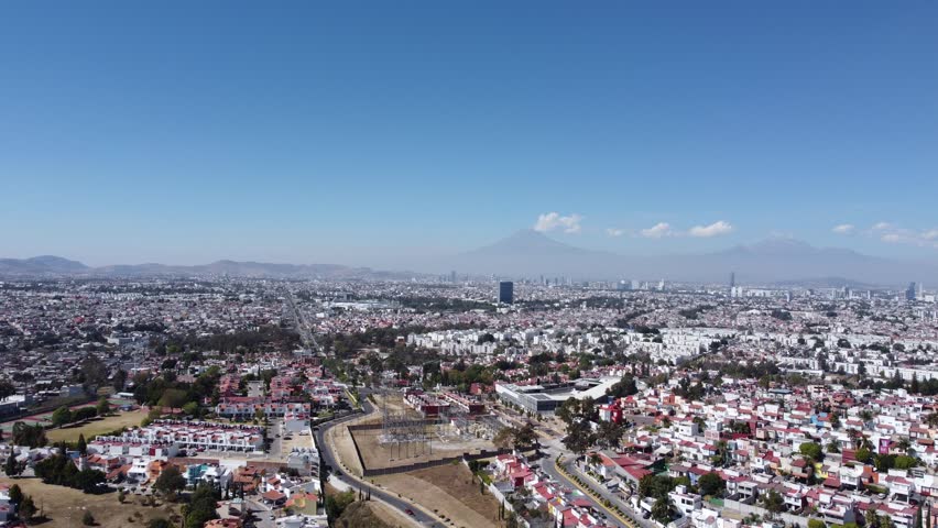View from the sky of the city of Puebla, in Mexico, with the Popocatépetl and Iztaccíhuatl volcanoes in the background | Shutterstock HD Video #1099528749