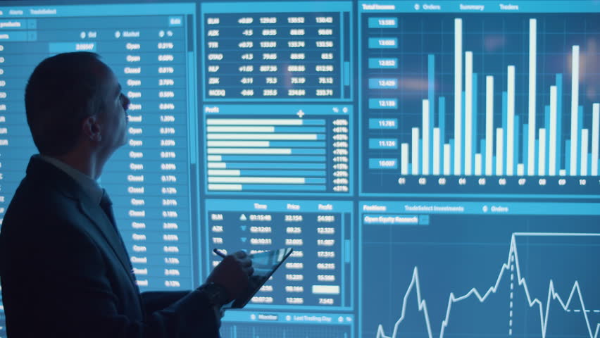 Man writing data on tablet from big digital screen. Back view of businessman in official suit in monitoring room processing analytics feed, looking at charts. Occupation, modern technology concept | Shutterstock HD Video #1099528793