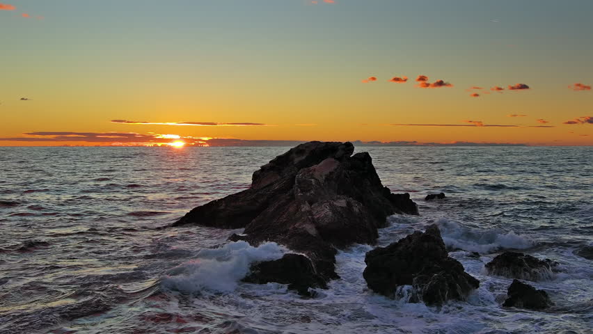 Aerial around view of sea and rocks during a beautiful colourful sunset, slow motion 4k