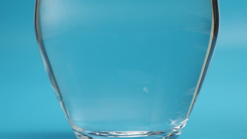 Effervescent tablet in a glass of water close-up on a blue background. Health concept. | Shutterstock HD Video #1099530151