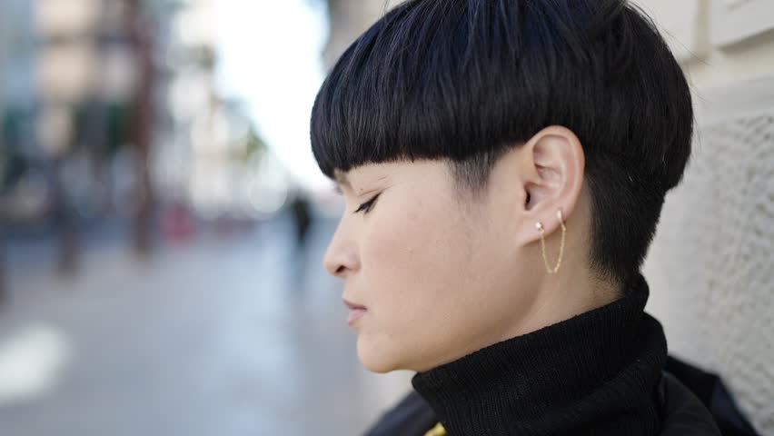 Young chinese woman standing with relaxed expression at street