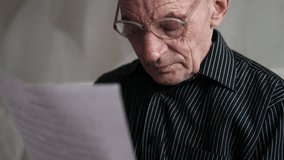 a caucasian pensioner in glasses carefully reads a piece of paper while being, a pensioner reads a bank notice, financial report, court decision, pre-bankruptcy, will - Powered by Shutterstock - Get 15% off with code: PIKWIZARD15