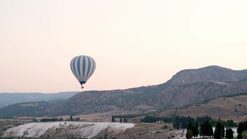 Aerial view hot air balloon flight over Natural travertine pools and terraces in Pamukkale early in the morning sunrse, Pamukkale geothermal springs, travertine terraces, ancient city of Hierapolis. | Shutterstock HD Video #1099543057